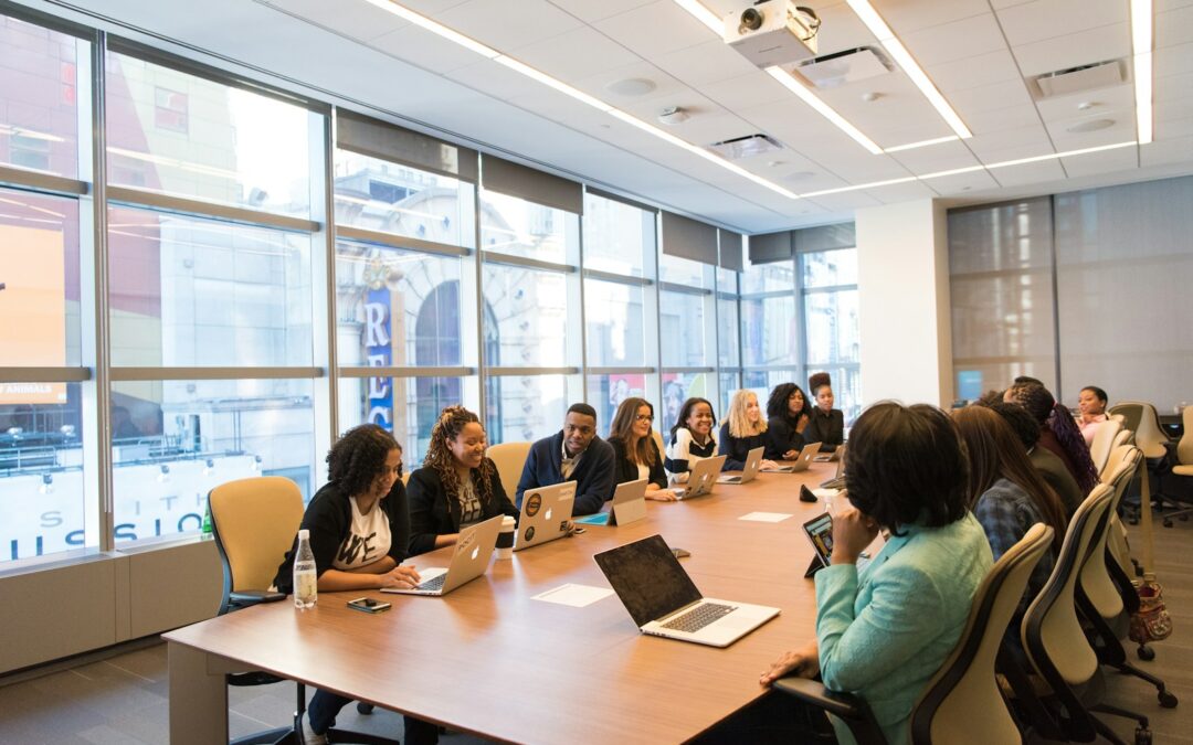 diverse group of people sitting beside rectangular wooden table with laptops